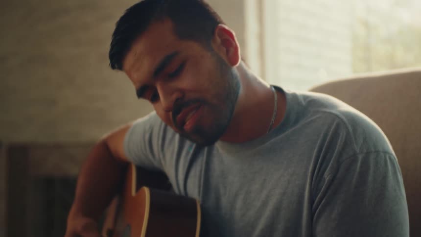 Man plays guitar in the sitting room while a boy sings along at daytime