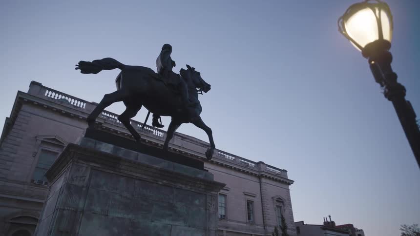 A footage of an horse rider statue standing in front of a building