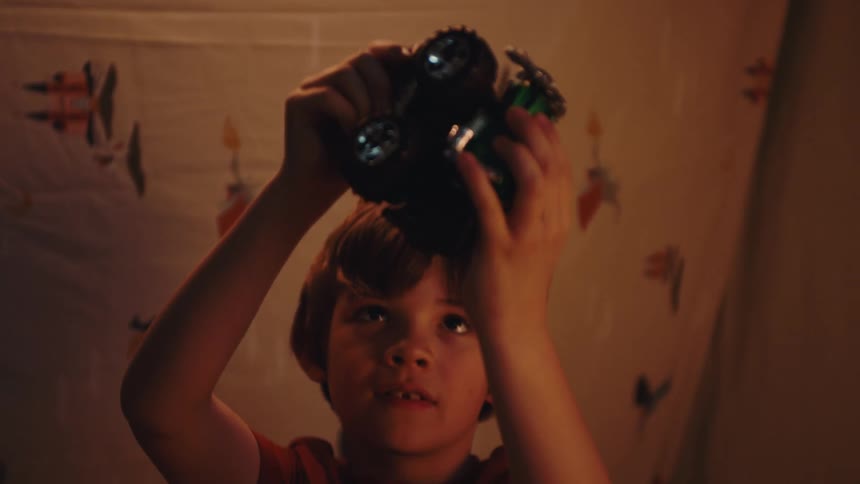 A happy little boy playing with a toy on a brown carpet