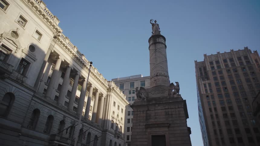 A lowangle orbiting camera shot circles a classical building and monument against a clear blue sky
