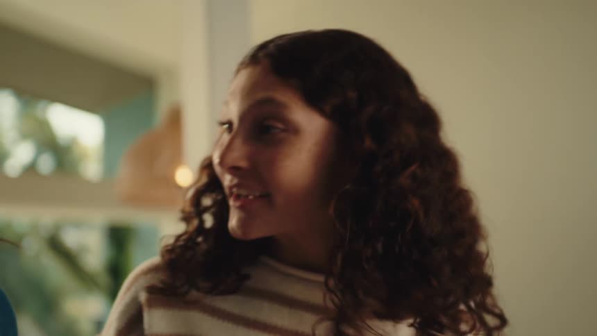 A woman smiles and nods while talking to another person beside her