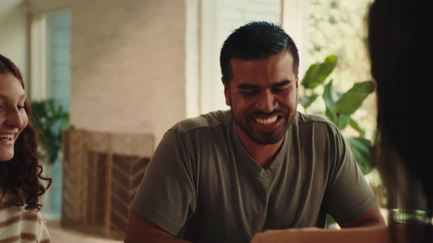 A man and a woman laughs while playing cards indoor at daytime