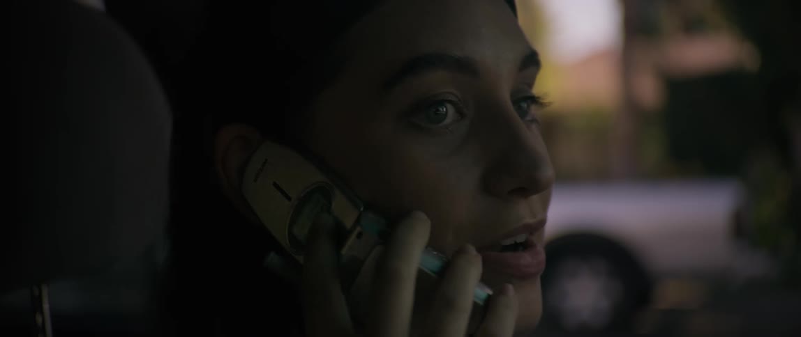 A woman picks up a phone call and looks from side to side as she converses