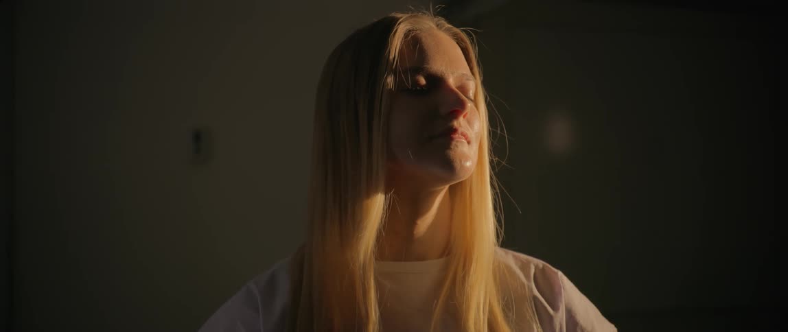 A patient sitting in a dark room enjoys the ray of sunshine caressing her face