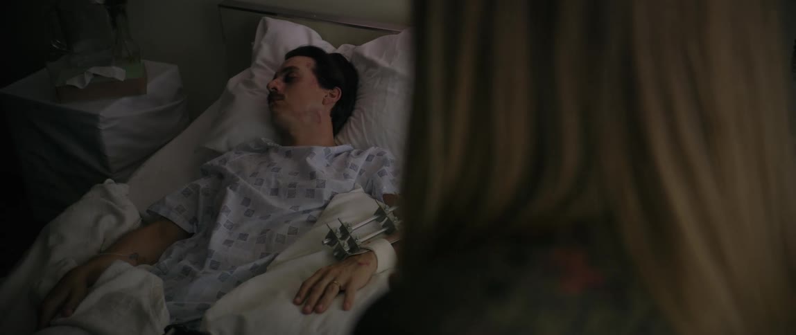 A visitor is standing over a sleeping hospital patient