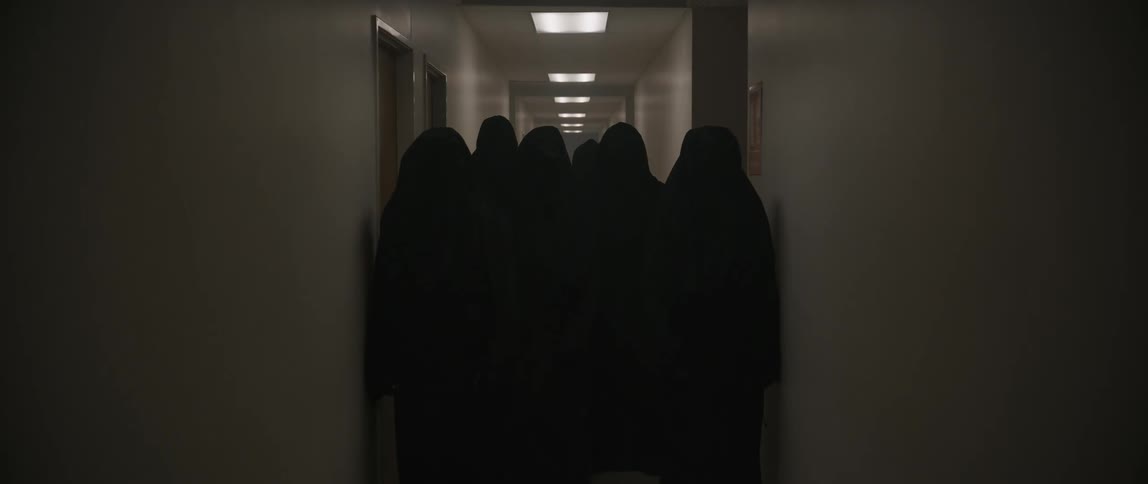A group of people in black robes fill the entire hallway