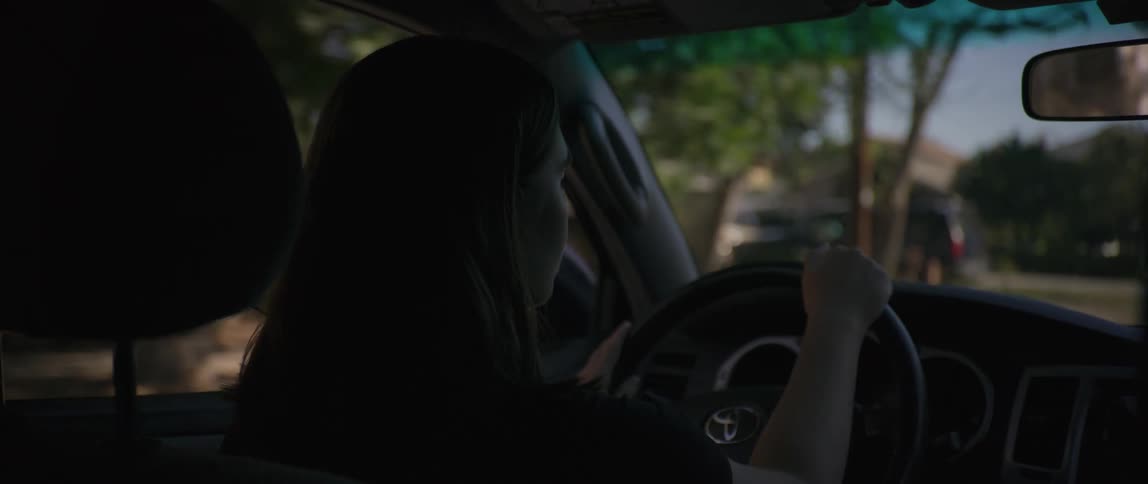 A woman is driving the car and moving the steering wheel then she immediately turns back and starts talking on the phone