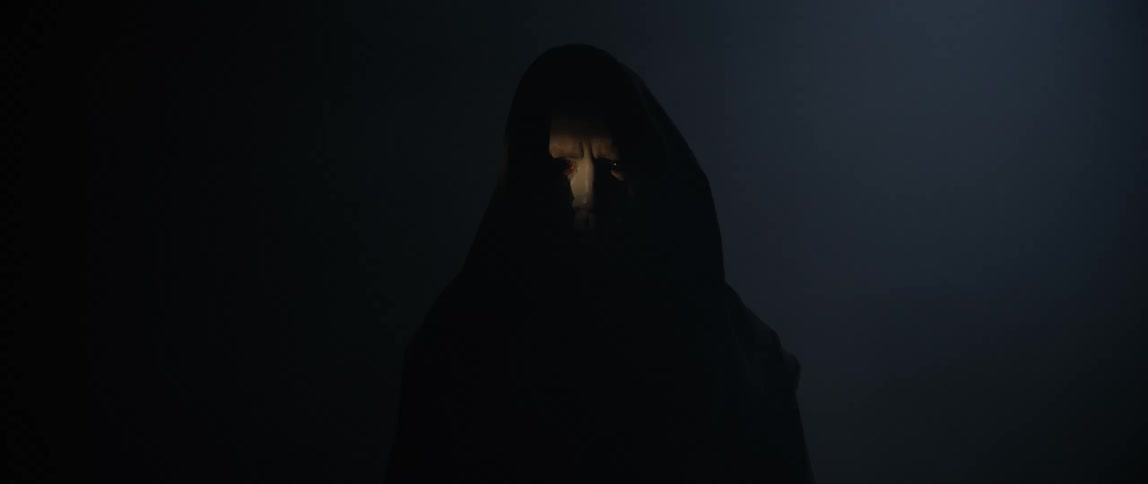 A man with black eyes slowly walks forward