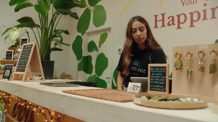 A young female walking behind a counter and getting on a laptop
