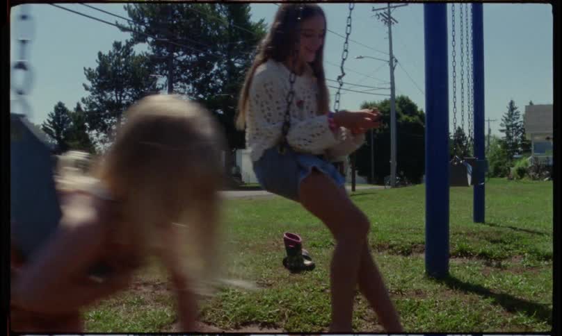 Two children playing on a swing in an outdoor anagram blind