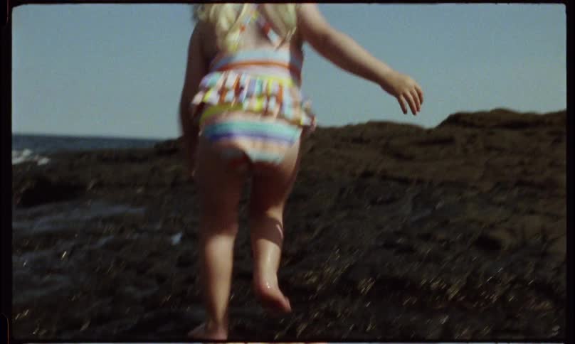 A girl walks on the rocks of the shore