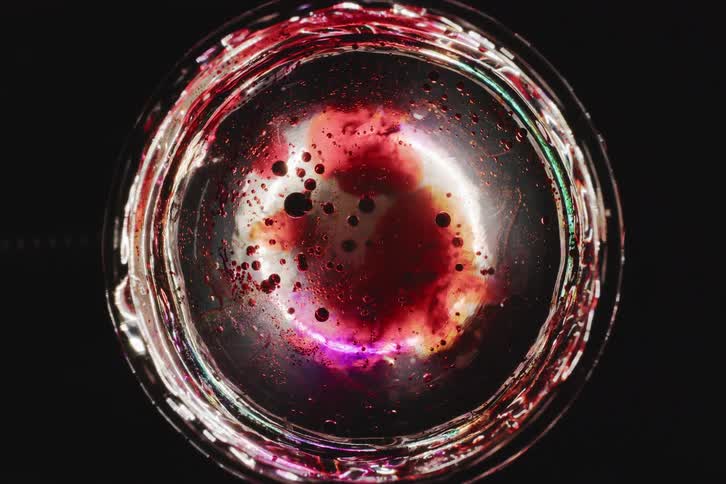 A white circular object with red particles inside rotating on its own axis