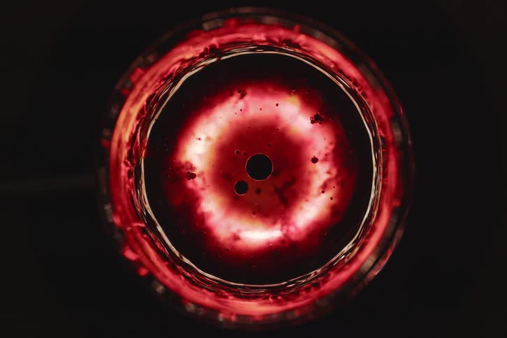 An abstract circular object in red that is rotating on its own axis
