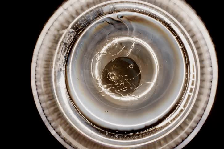 An extreme closeup of a lightbulb or lenslike object emphasizing abstract textures and reflections in a circular pattern