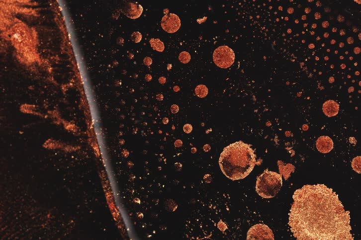 The crimson ink is moving around in small bubbles