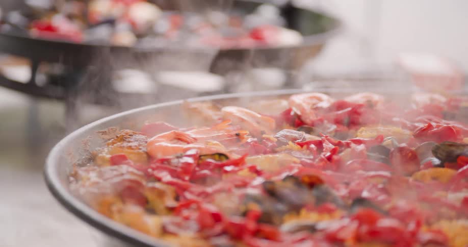 A cook is putting shrimp into the large pan