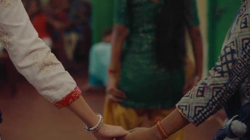 Two women hold hands and separate them shortly after