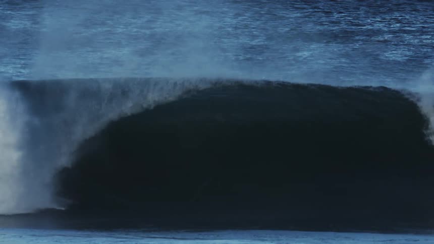 A man surfing riding a large wave on a windy morning