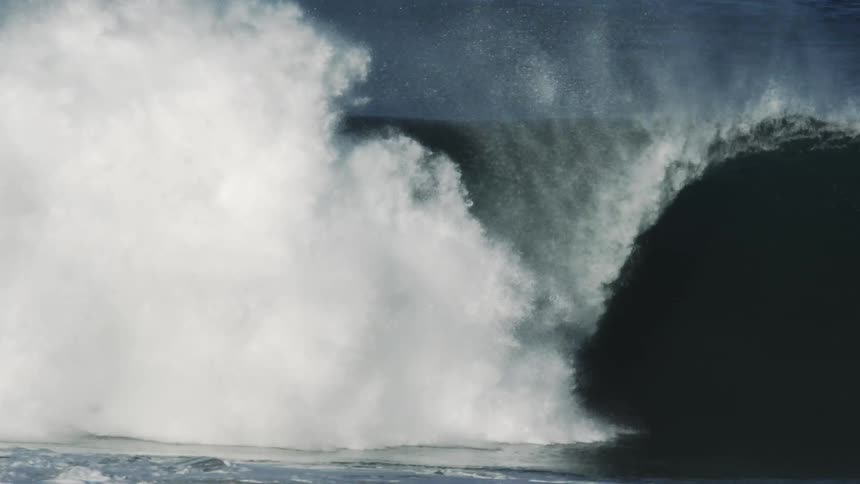 Surfer riding a huge wave as it curls and covers him with water