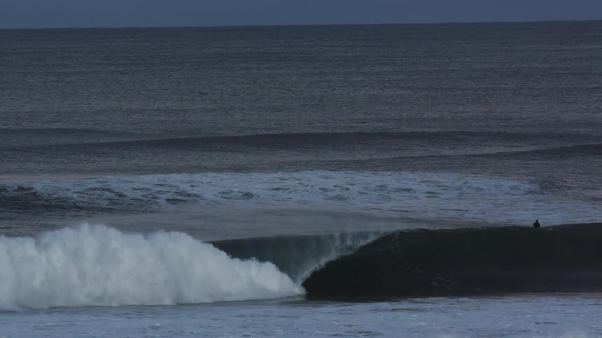 Aerial of large wave forming and crashing in the ocean