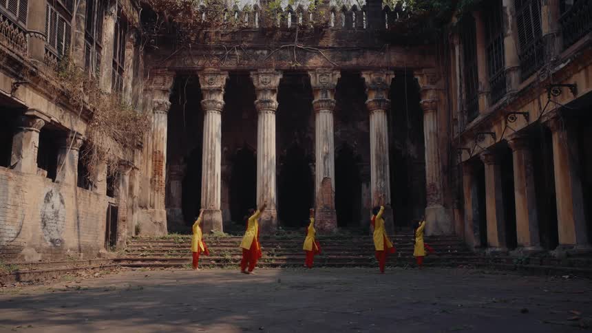 A group of dancers practice in front of a flight of stairs in a court yard