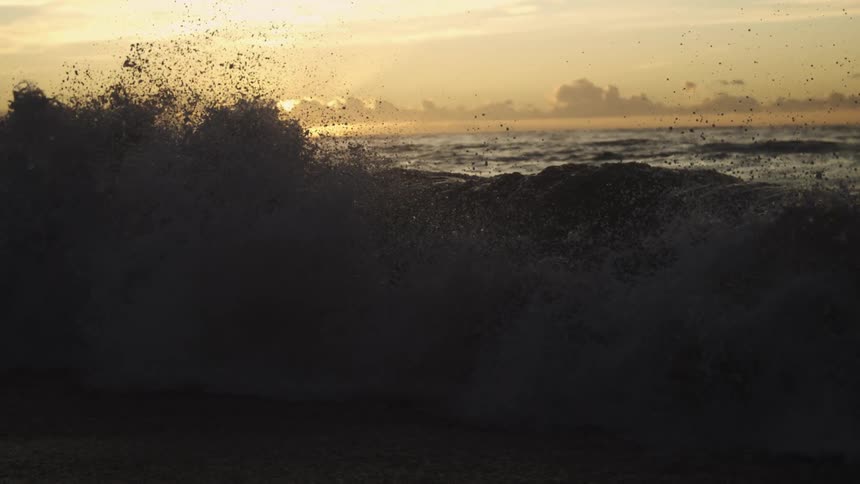 A large wave crashes into the shoreline