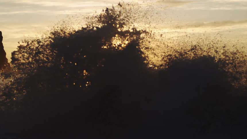 A small ocean wave breaking on the beach and making a splash of drops upwards