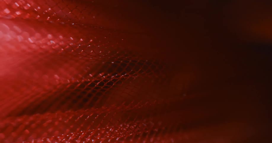 An abstract red object full of small holes and going to the right