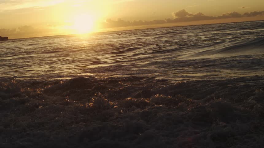 The sea with waves during sunset under a cloudy sky