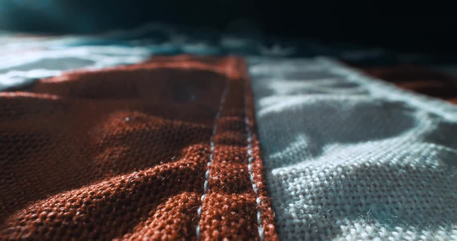 A closeup abstract shot of textured stitched fabric with dramatic lighting and shallow depth of field