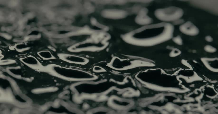 Thin layer of liquid covers the surface of a textured greenish mass