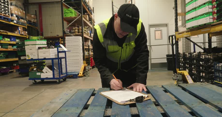 Inspector inside a warehouse making notes in a notebook