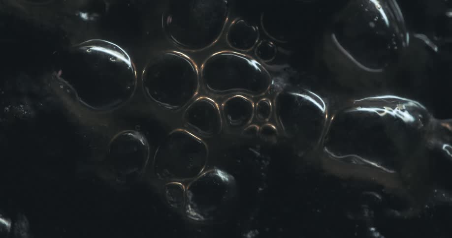 Bubbles of different sizes cluster together on a dark surface
