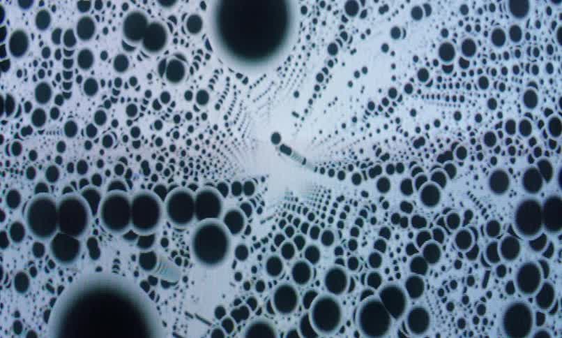 Infinite loop of patterned black polka dots against an abstract white background