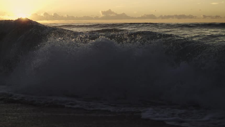 Wave crashing in slow motion as the sun sets in the ocean
