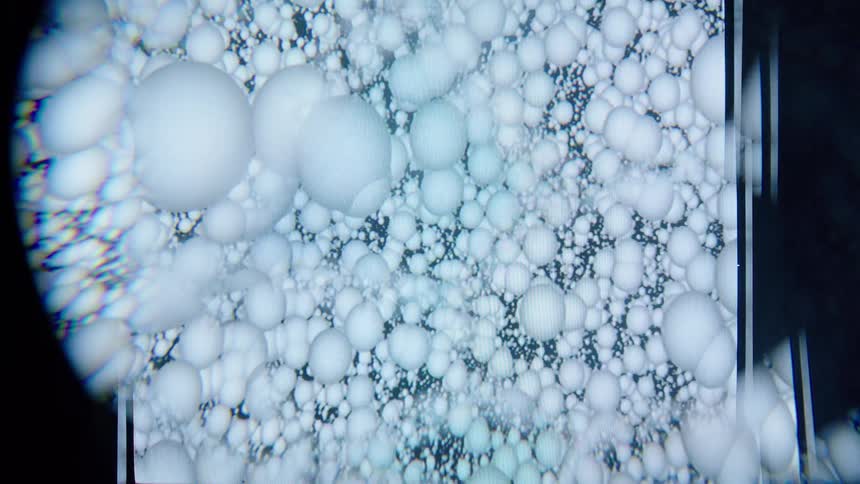 Whitish spheres in an abstract loop against a dark background