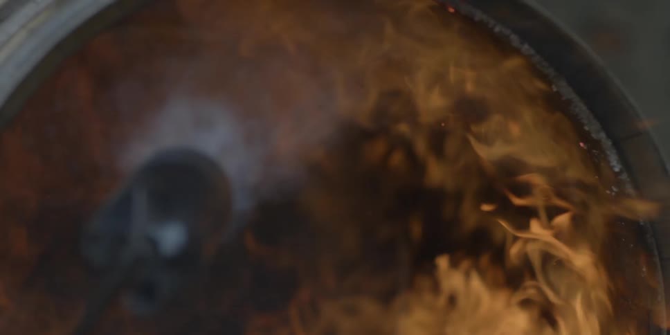 A person is using a torch on a barrel