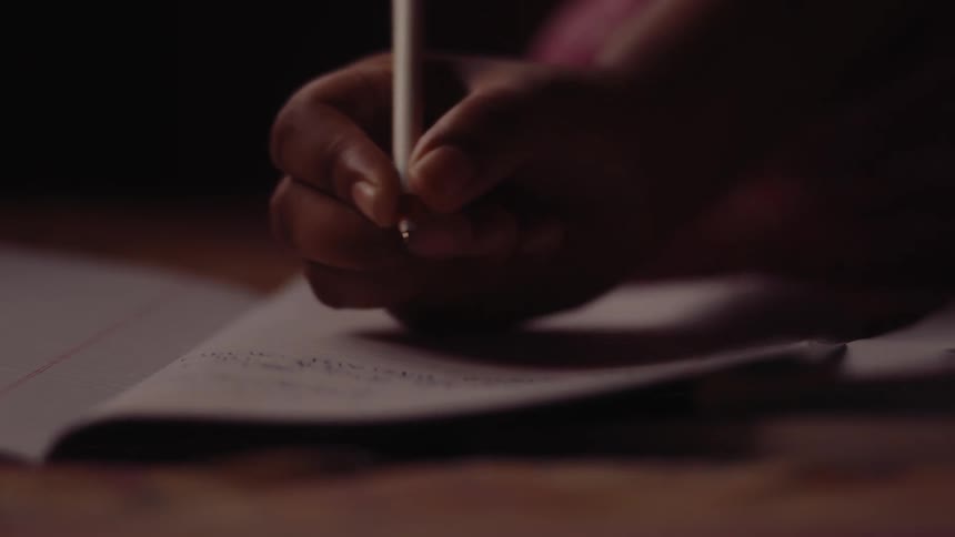 A person writes with a pen in a notebook