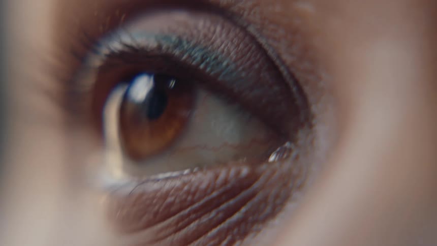 An extreme closeup of a human eye reflects its surroundings in a highly detailed intimate shot