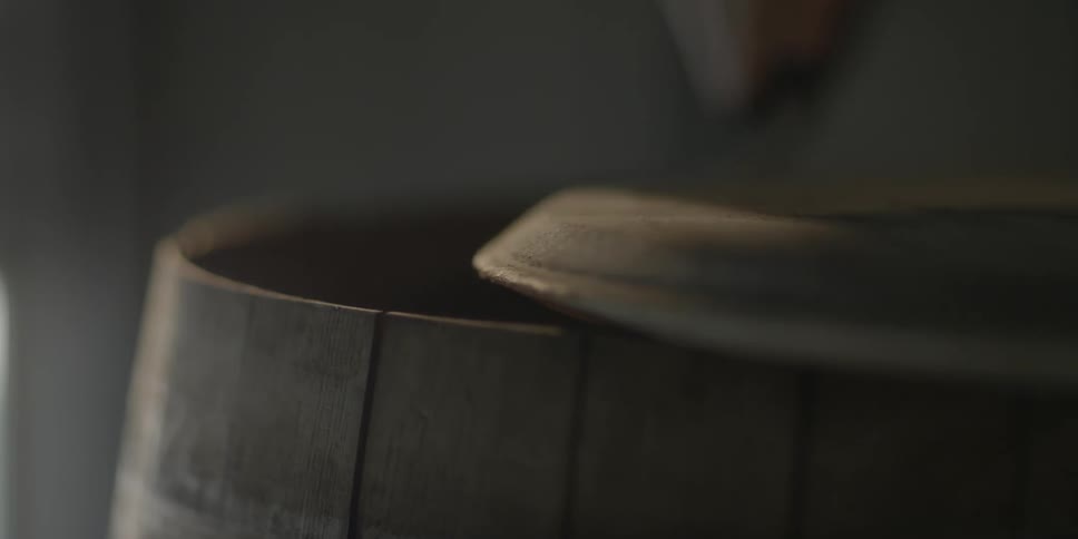 A person is shaving the lid of a barrel