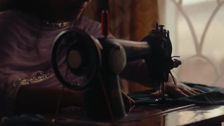 A woman uses her showing machine to sew an article of clothing