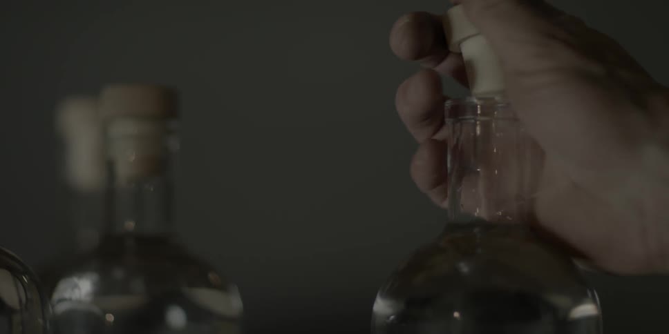 Person moving a bottle and putting a cork in it