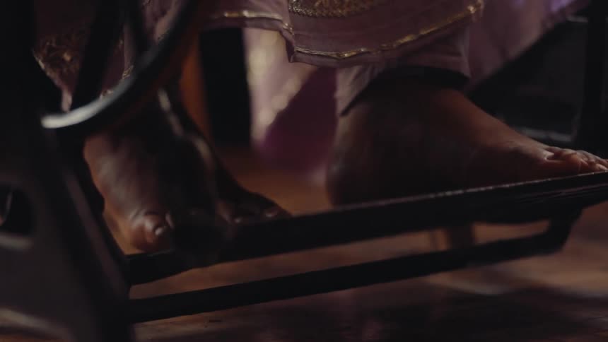 A womans bare feet work the pedal of a sewing machine