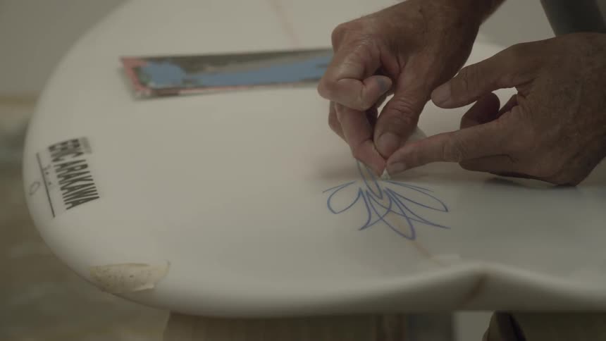 A person is putting decals on a surfboard