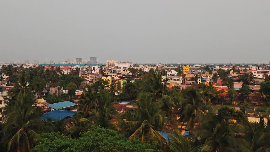 Aerial view of a dense colorful neighborhood with palm trees under a cloudy sky