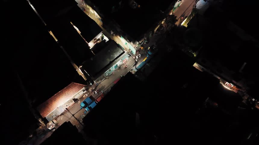 Aerial view of scooters and motorcycles driving along a busy street at night