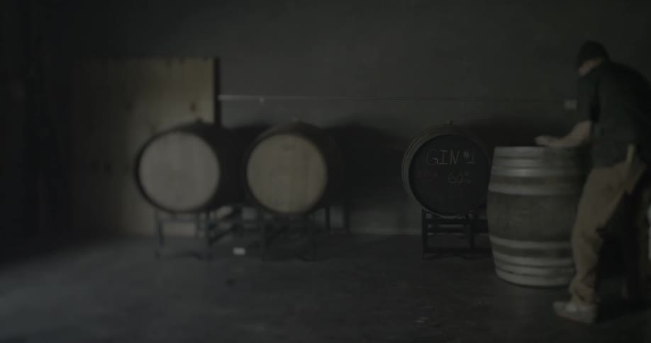 A man is moving a large barrel and putting it on a stand