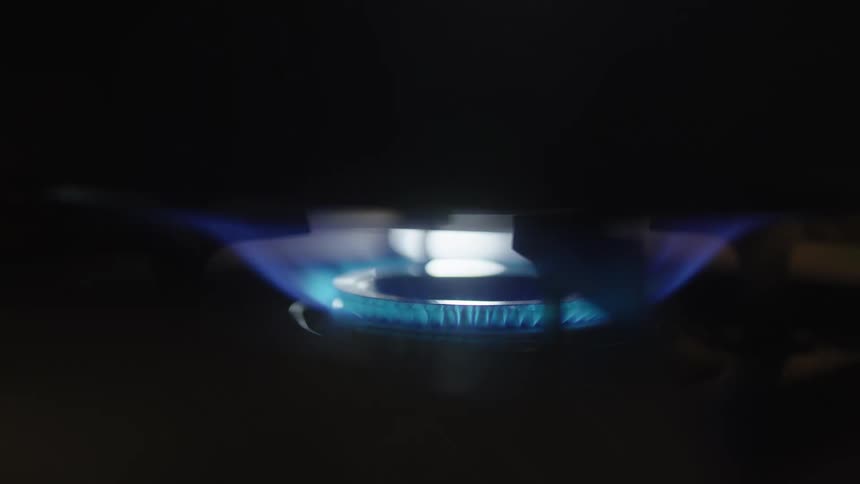 A black frying pan is placed on a lit gas stove