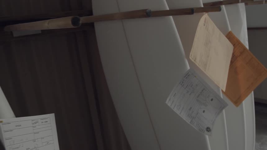 Unfinished surfboards and lined up on a wall
