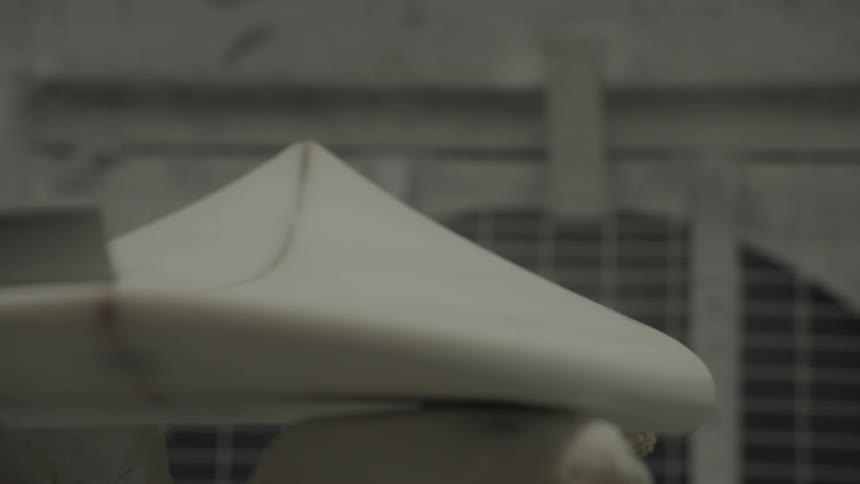 A person is using a sander on a surfboard